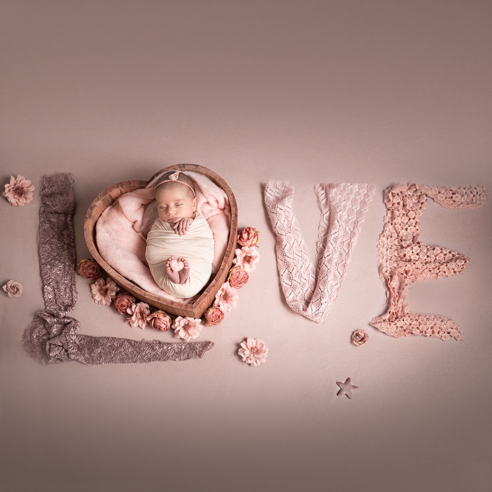 Neonata nel cuore di legno con la scritta LOVE in pizzo rosa